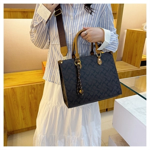 Detail of vintage monogram tote bag with leather handles and metallic ring charm