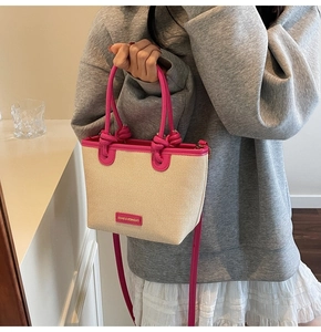 Dettaglio borsa a secchiello intrecciata a mano con finiture in ecopelle rosa acceso