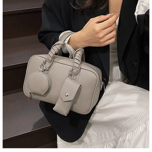 Detail of grey pebble leather Boston bag featuring woven handles and attached pouches