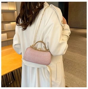 Modèle portant une pochette de soirée rose pailletée avec chaîne dorée sur manteau blanc