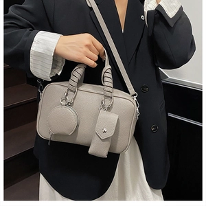 Detail of grey lychee leather handbag featuring wrapped handle and modular mini pouches