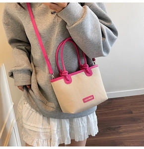 Detailansicht der gewebten Beuteltasche mit rosa Griffen an einem Model-Outfit