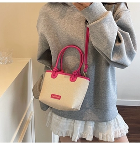 Detail der beigen geflochtenen Beuteltasche mit pinkfarbenen Ledergriffen und Gurt
