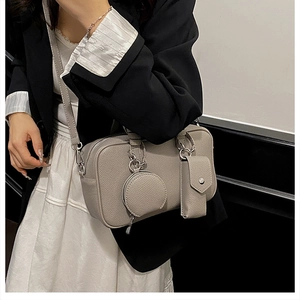 Detail of grey lychee leather Boston bag featuring round and rectangular bag-in-bag charms