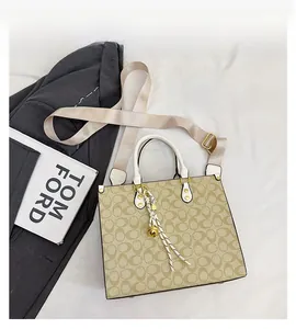 Detail of printed tote bag with leather handles, woven strap and gold-tone metal hardware