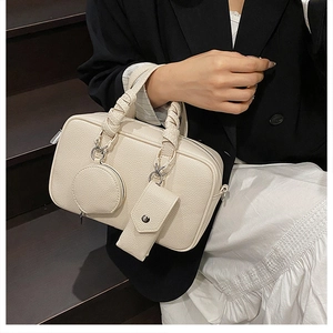 Detail of off-white lychee pattern Boston bag with woven handle and hanging accessory pouch