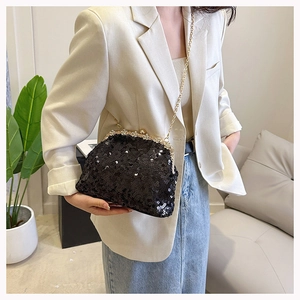 Close-up of black sequined evening bag with ornate gold metal clasp and thin chain strap