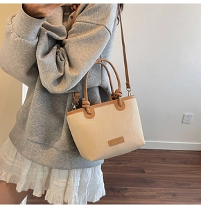 Detail of knot handle and leather strap on a large straw shoulder bucket bag