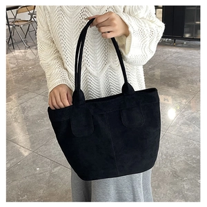 Détail d'un grand sac cabas en daim noir avec lignes décoratives et longues anses de transport