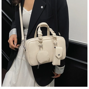 Detail of cream Boston bag with woven handles and detachable accessory pouches