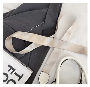 Detail of wide cream woven bag strap with white leather attachment and fabric texture
