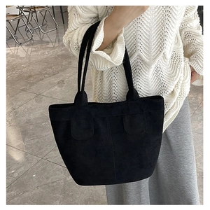 Gros plan sur un sac cabas en daim noir mat avec deux poignées et des coutures décoratives