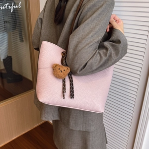 Pink lychee texture tote bag with brown straps and cute bear charm worn by a model
