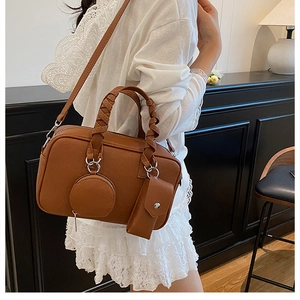 Detail of a brown leather Boston bag with woven handles and small hanging pouches