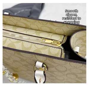 Close-up of the smooth golden metal zipper on the vintage monogram pattern tote bag