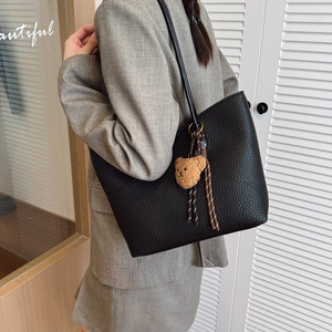 Large black pebbled leather tote bag with a cute brown teddy bear charm on model shoulder