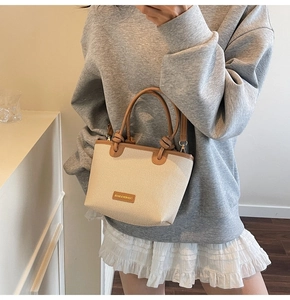 Detail of canvas bucket bag with brown leather trim and knotted handle design