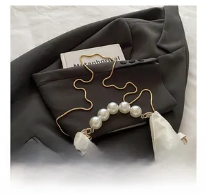 Detail of white snakeskin texture bag with large pearl handle and gold snake chain