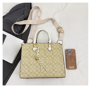 Detailed top view of beige patterned tote bag with gold charms and white handles