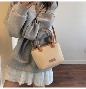 Close-up of beige woven basket bag with brown leather handles and adjustable strap