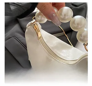 Detail of white snakeskin texture handbag with large pearls handle and golden zipper