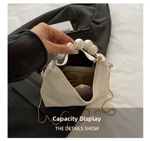 Detail showing the internal capacity of the white pearl handbag with gold chain strap