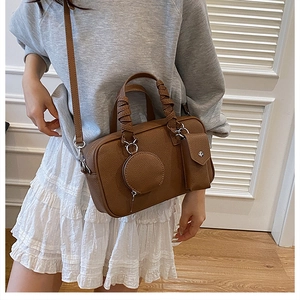 Detail view of brown pebbled leather Boston bag with woven handles and detachable pouches