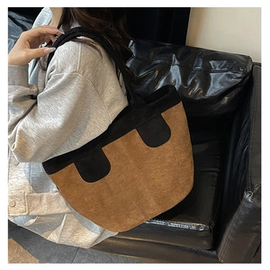 Sac fourre-tout marron et noir porté par un mannequin sur un canapé en cuir pour taille