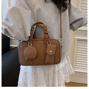 Detail of caramel lychee texture Boston bag with woven handle and modular pendant charms