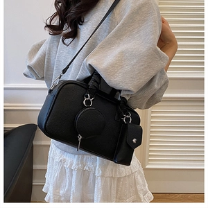 Three-piece black lychee leather crossbody bag set with round coin pouch shown on model