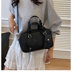 Detail of black lychee leather handbag with wrapped handles and mini pouch charms