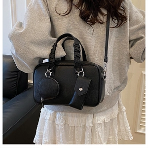 Detail of black Boston bag featuring textured leather, woven handles and three-in-one pouches