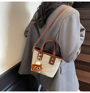 Canvas and leather bucket bag detail with Fashion & Bags text and plush pendant charm