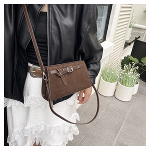 Sac bandoulière marron en daim porté avec veste en cuir et robe longue blanche