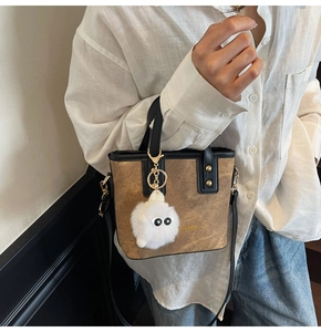 Close-up of brown crossbody bag with ON & BAGS print and a cute plush doll charm