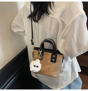 Detail of brown leather bucket bag with cute eye plush charm and fashion embossing