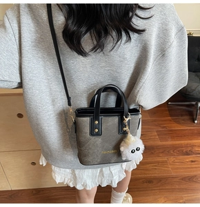 Close-up of retro mini bucket bag with leather handles and plush monster charm