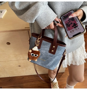 Detail of blue denim patchwork tote with leather handles and cute plush charm