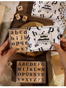 Hände halten ein Vintage-Holzbuchstaben-Stempelset in einer minimalistischen Papierbox