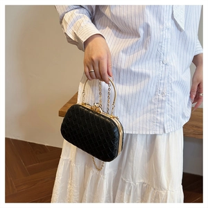 Detail of woven black evening bag with gold chain strap and elegant circular handle