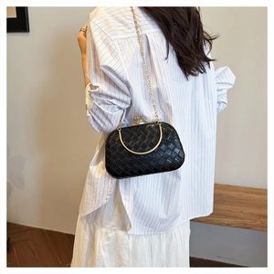 Detail showing woven black box bag with gold metal handle and chain strap on person