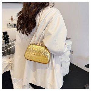 Detail of woven gold evening bag featuring a round metal handle and diamond-set clasp