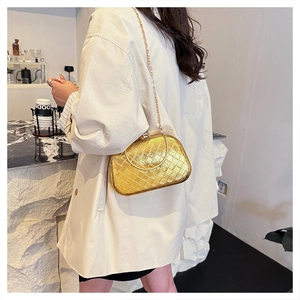 Close-up of golden quilted cross-body bag with elegant chain strap and textured finish
