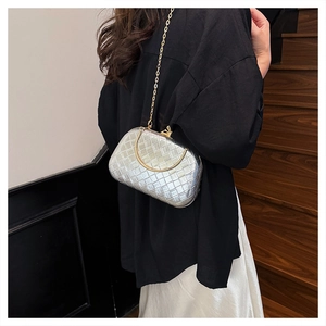 Close-up of silver woven texture evening bag with gold metal handle and chain strap