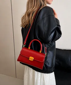 Detalle de bolso bandolera vintage de cuero rojo oscuro con hebilla dorada en un modelo