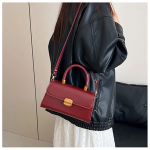 Detalle de bolso vintage rojo vino en cuero encerado con hebilla metálica dorada