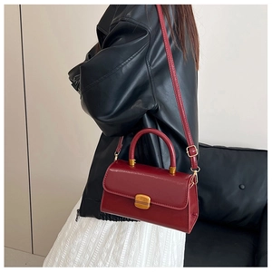 Detalle de bolso vintage de cuero rojo con cierre giratorio dorado y correa ajustable