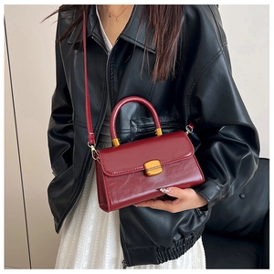 Detalle de bolso vintage burdeos en cuero encerado combinado con chaqueta elegante
