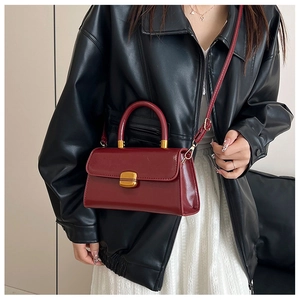 Bolso cuadrado de cuero burdeos con hebilla dorada en modelo con chaqueta de piel