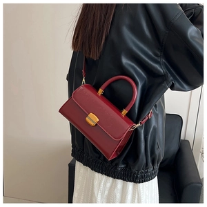 Bolso de mano rojo oscuro en cuero encerado con cierre de metal dorado en estilo moderno
